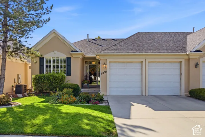 Stucco exterior with a pitched shingle roof, bay window with shutters, and an attached two-car garage
