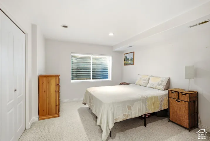 Recessed lighting, carpet flooring, a window with horizontal blinds, and a built-in closet with bifold doors