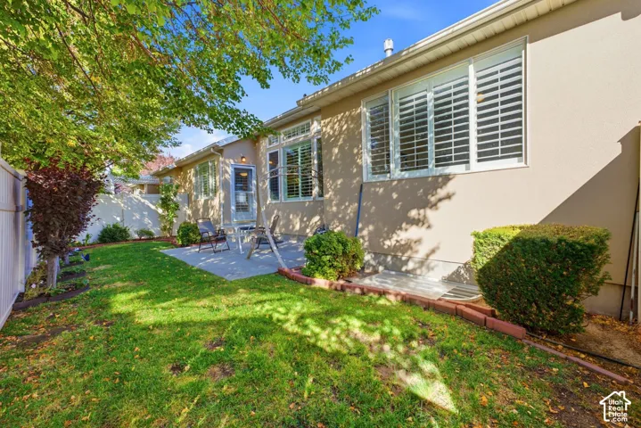 Expansive green lawn with a privacy fence, mature trees, and a concrete patio