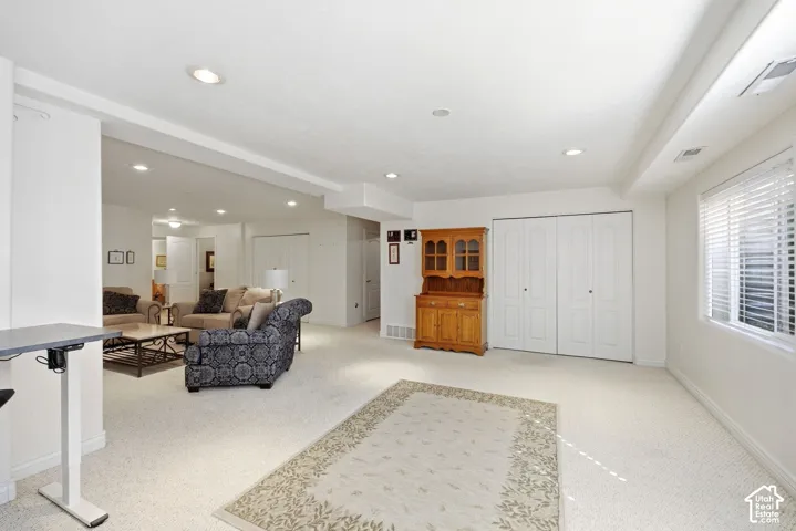 Recessed lighting, carpet flooring, a window with horizontal blinds, and bi-fold closet doors