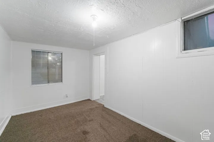 Recessed windows, white paneling, textured ceiling, brown carpet flooring