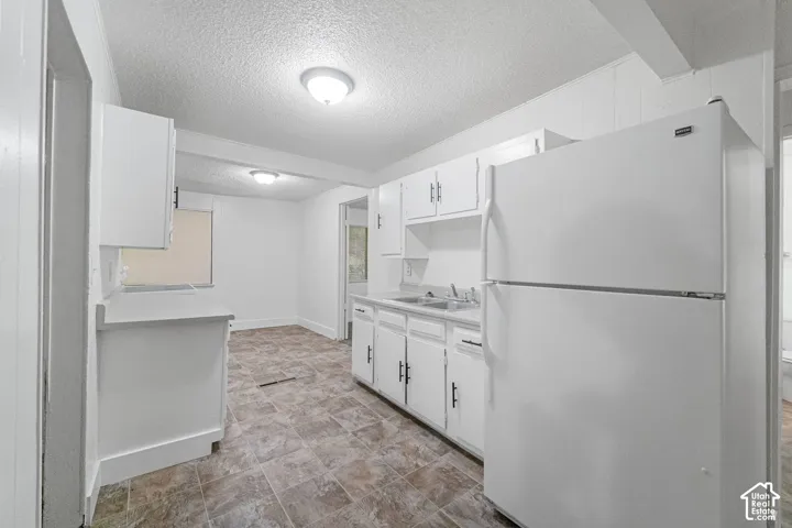 Kitchen featuring white cabinetry, white appliances, and a double basin sink