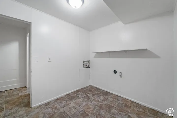 Tile flooring with an open doorway, overhead lighting, and wall-mounted shelving