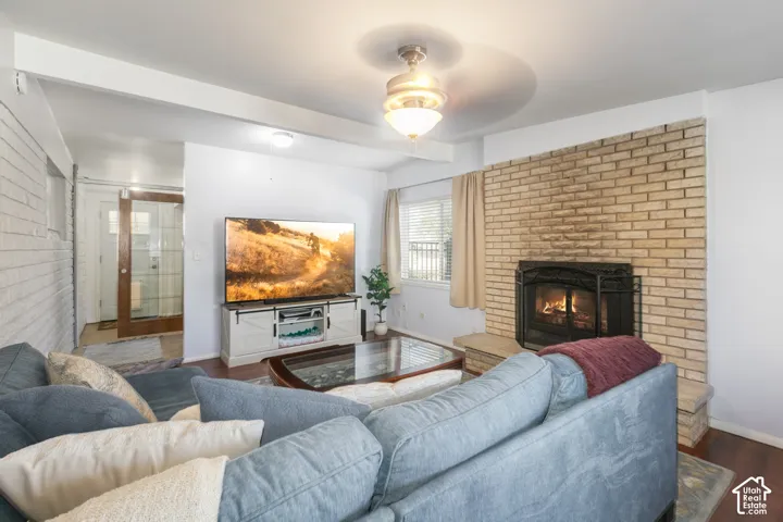 Brick fireplace with a black metal insert, wood-finish flooring, and white painted walls