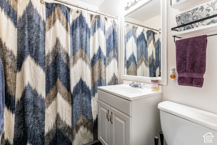 White vanity with integrated sink, chrome faucet, framed wall mirror, and wall-mounted shelving