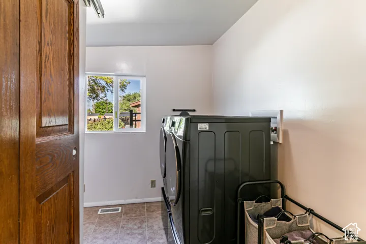 Laundry area with a wood-paneled sliding door, tiled flooring, and a window