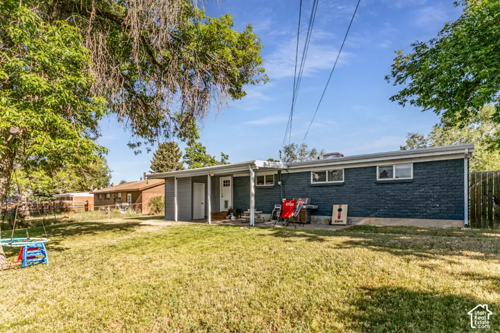 Rear exterior with blue brick facade, covered patio, and a grass lawn