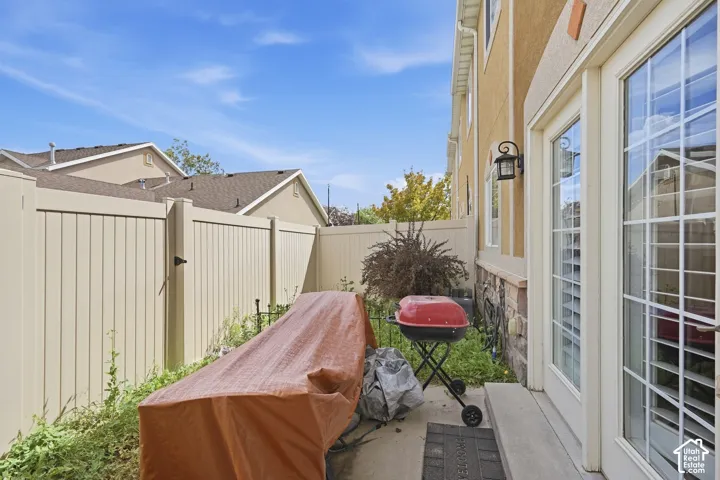 Patio access with grid-pane glass door, stone veneer exterior, outdoor wall sconce, and privacy fencing