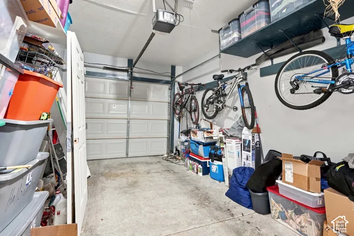 Attached garage with a panel-style door, concrete flooring, and overhead storage shelving