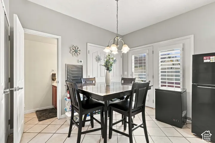 Light-toned tile flooring, white interior doors, and a decorative chandelier with frosted glass shades