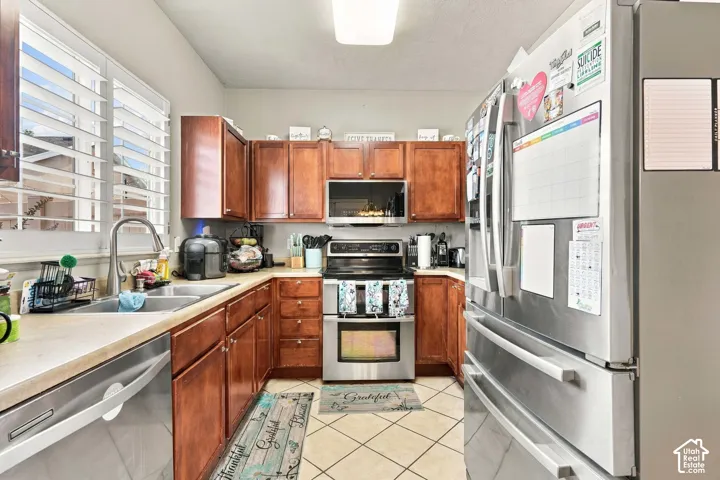 Kitchen featuring wood cabinetry, stainless steel appliances, a double basin sink, and shuttered windows