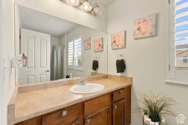 Primary ensuite Built-in vanity with an integrated sink, wood-finish cabinetry, and a full-width wall mirror