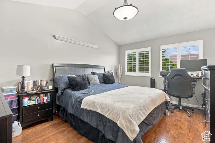 Primary Bedroom Vaulted ceiling with an attached light fixture, wood-finish flooring, and dual windows with plantation shutters with 2 Walk In closet areas