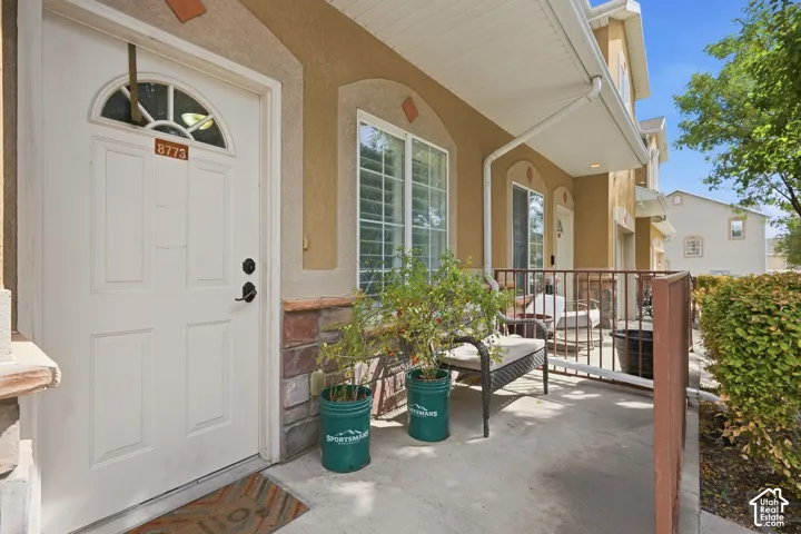 Entry door with an arched transom window, a covered front porch, and a stone facade accent