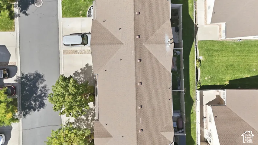 Pitched roofline with brown shingles, private rear yard with green lawn, and dedicated parking spaces