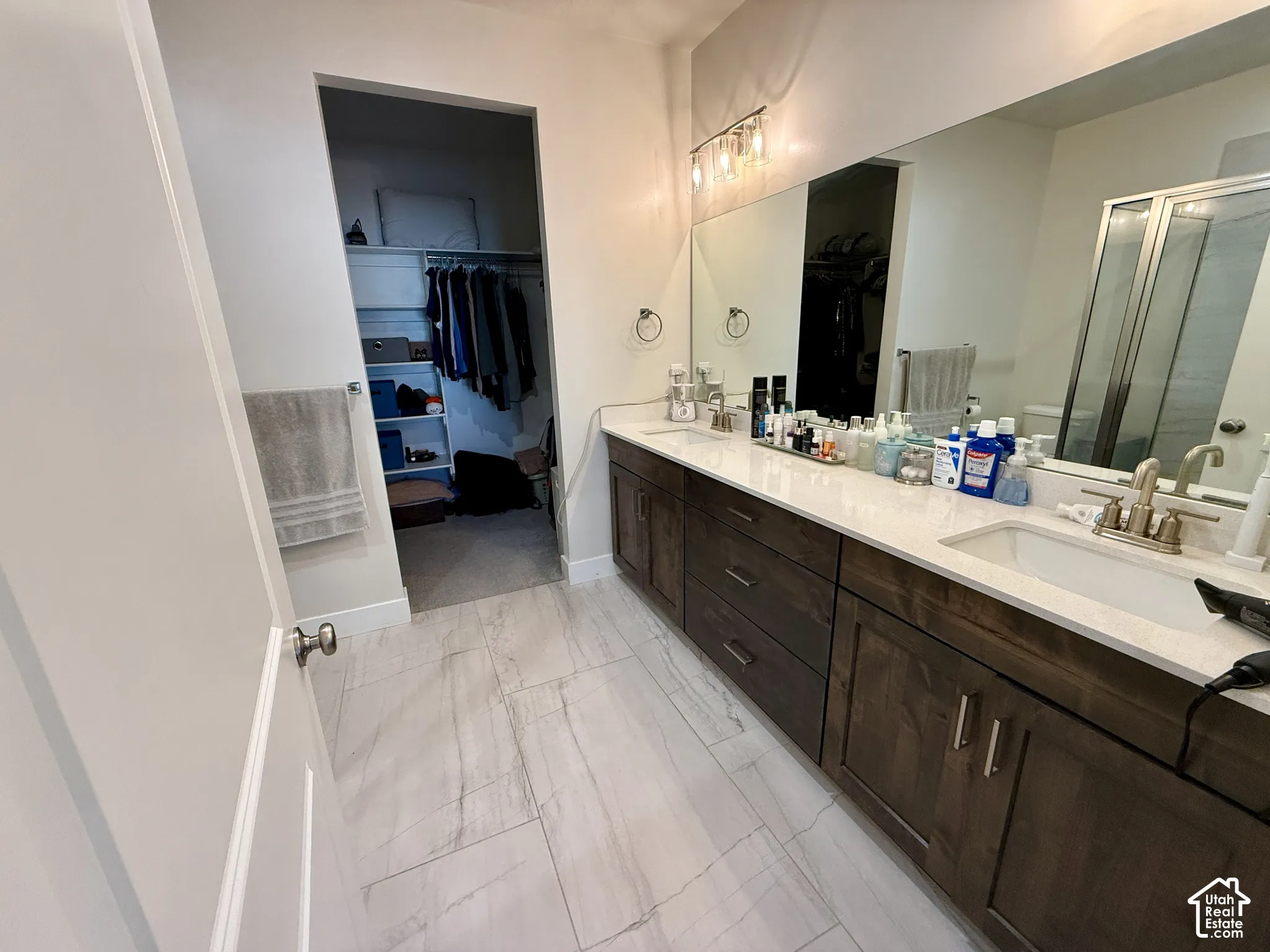 Dual vanity with undermount sinks, wood-finish cabinetry, and light-toned countertops