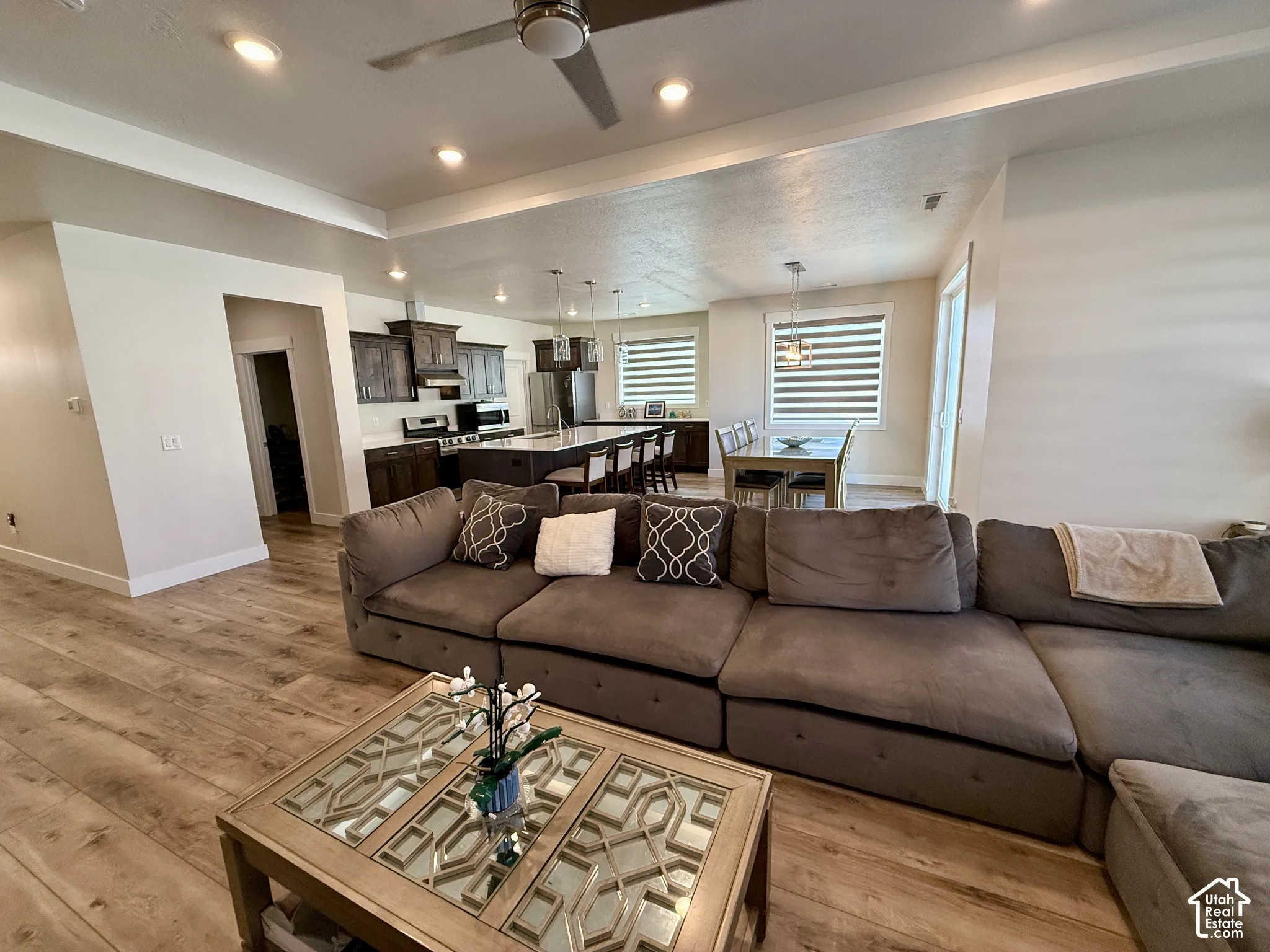 Open-concept living space featuring wood-finish flooring, recessed lighting, and a ceiling fan