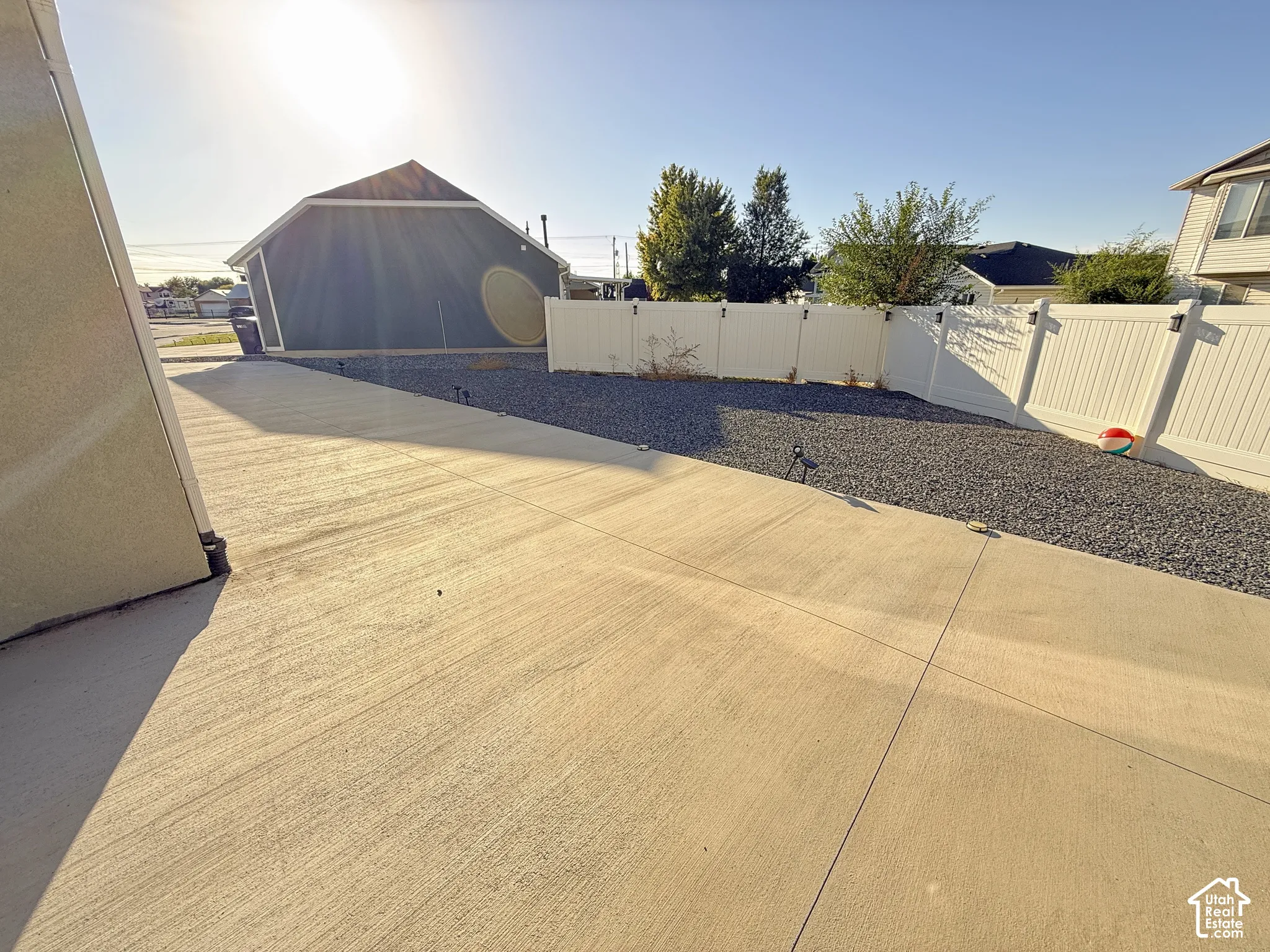 Concrete driveway with a gravel border and white privacy fencing