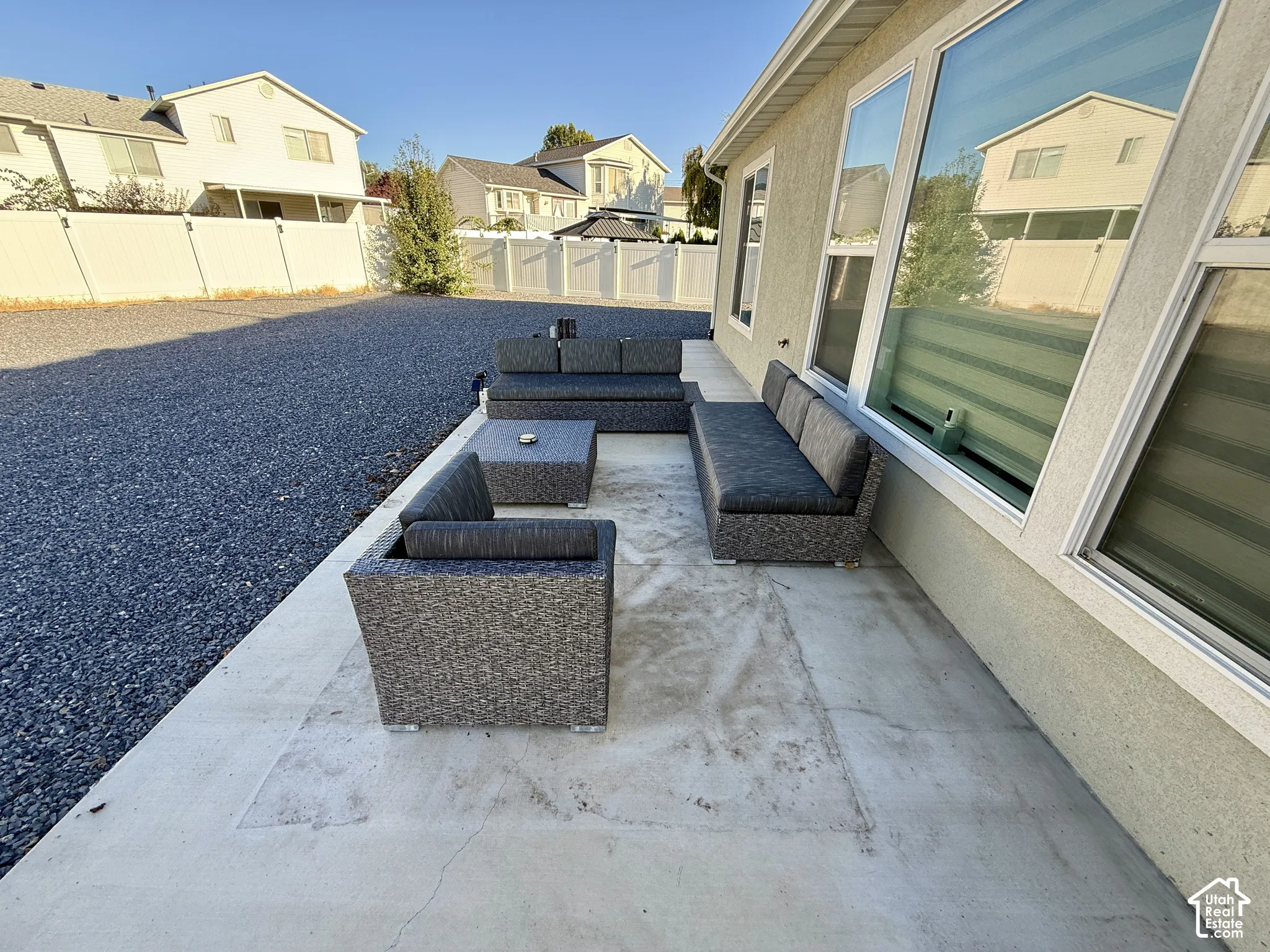 Exterior patio with concrete hardscaping, large pane windows, and gravel landscaping