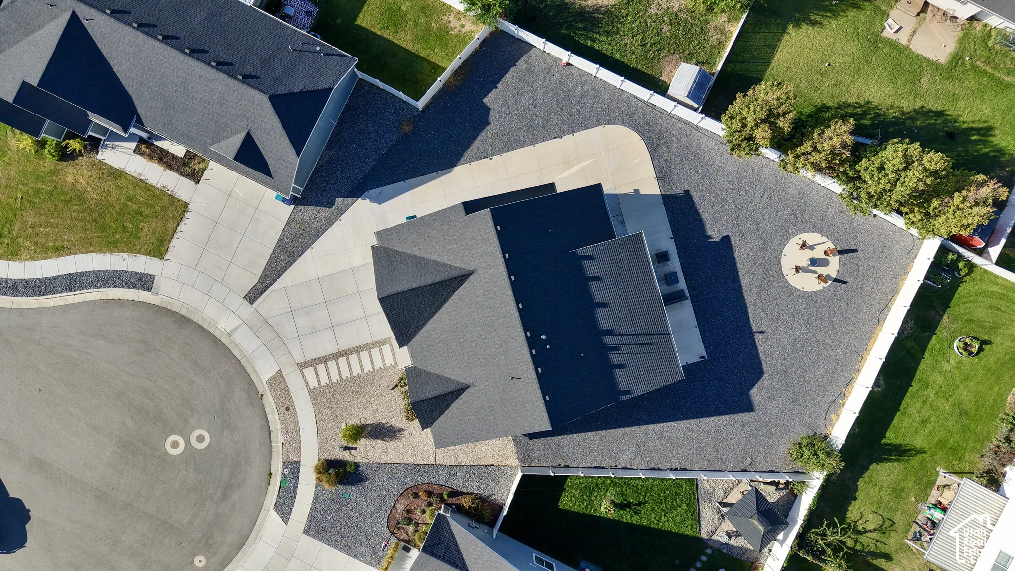 Extensive paved driveway and parking area, mature landscape plantings, and multiple rooflines with dark shingles