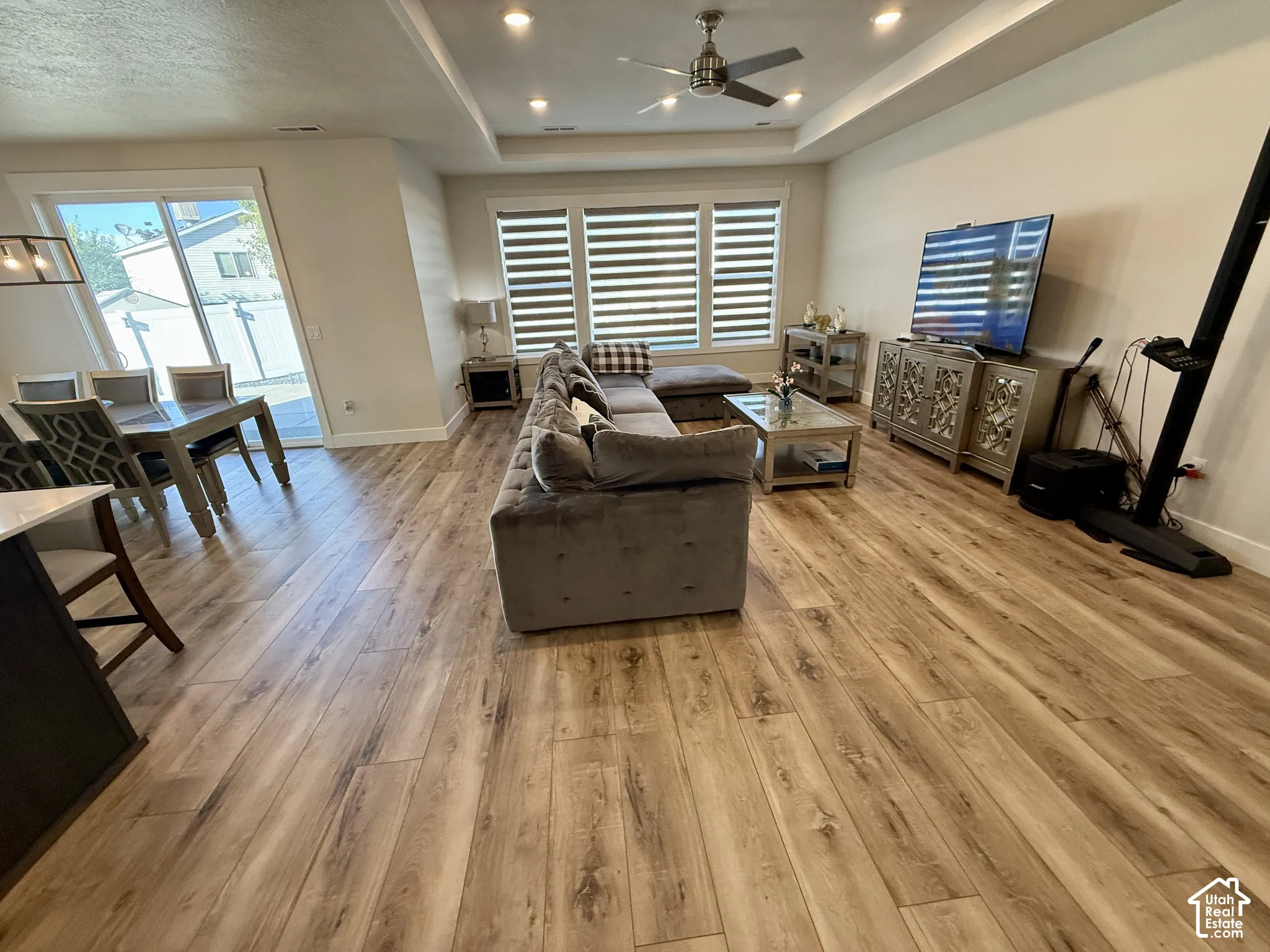 Open-concept living area featuring wood-finish flooring, recessed lighting, and a tray ceiling