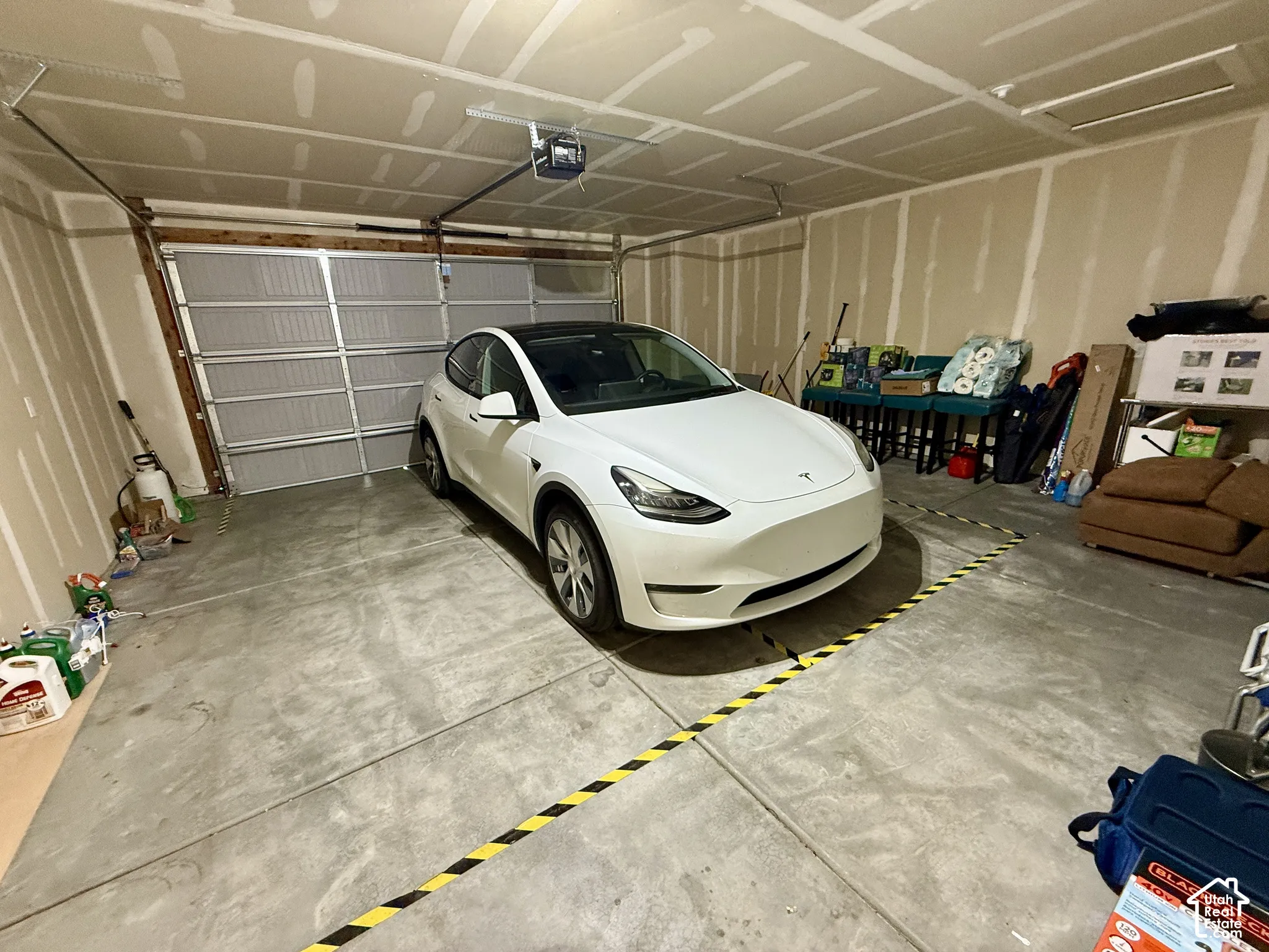 Spacious garage with exposed drywall, concrete flooring, and an overhead garage door