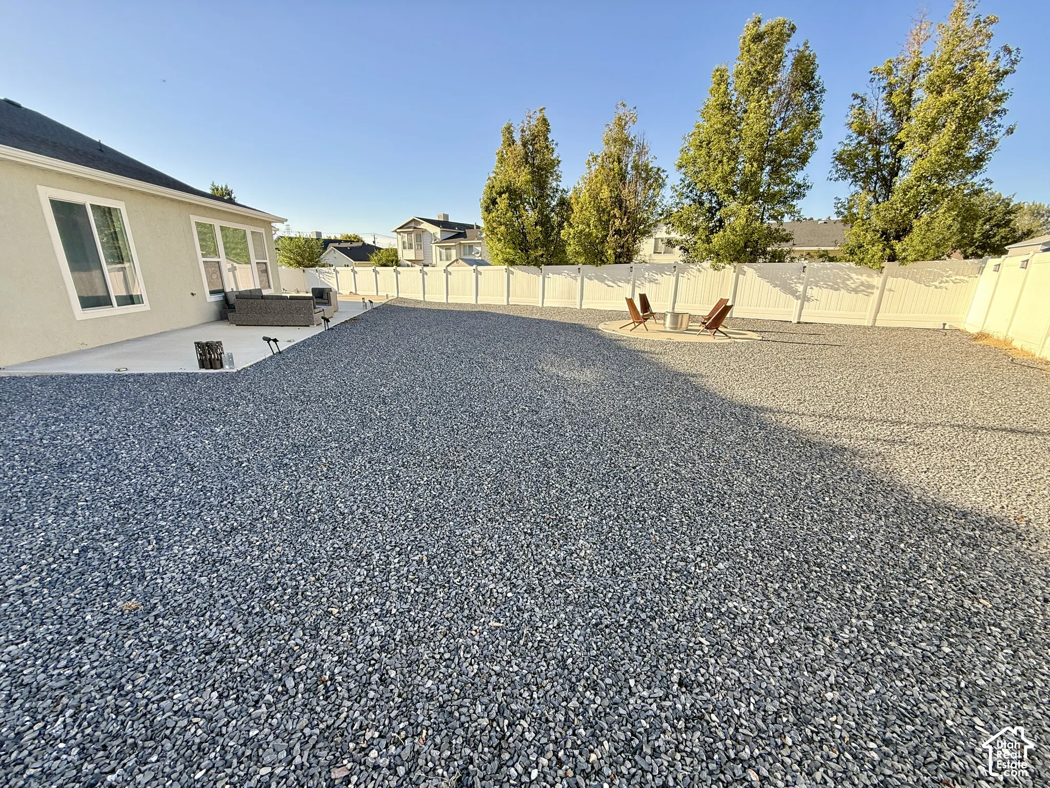 Expansive backyard featuring a gravel surface, concrete patio, and privacy fencing