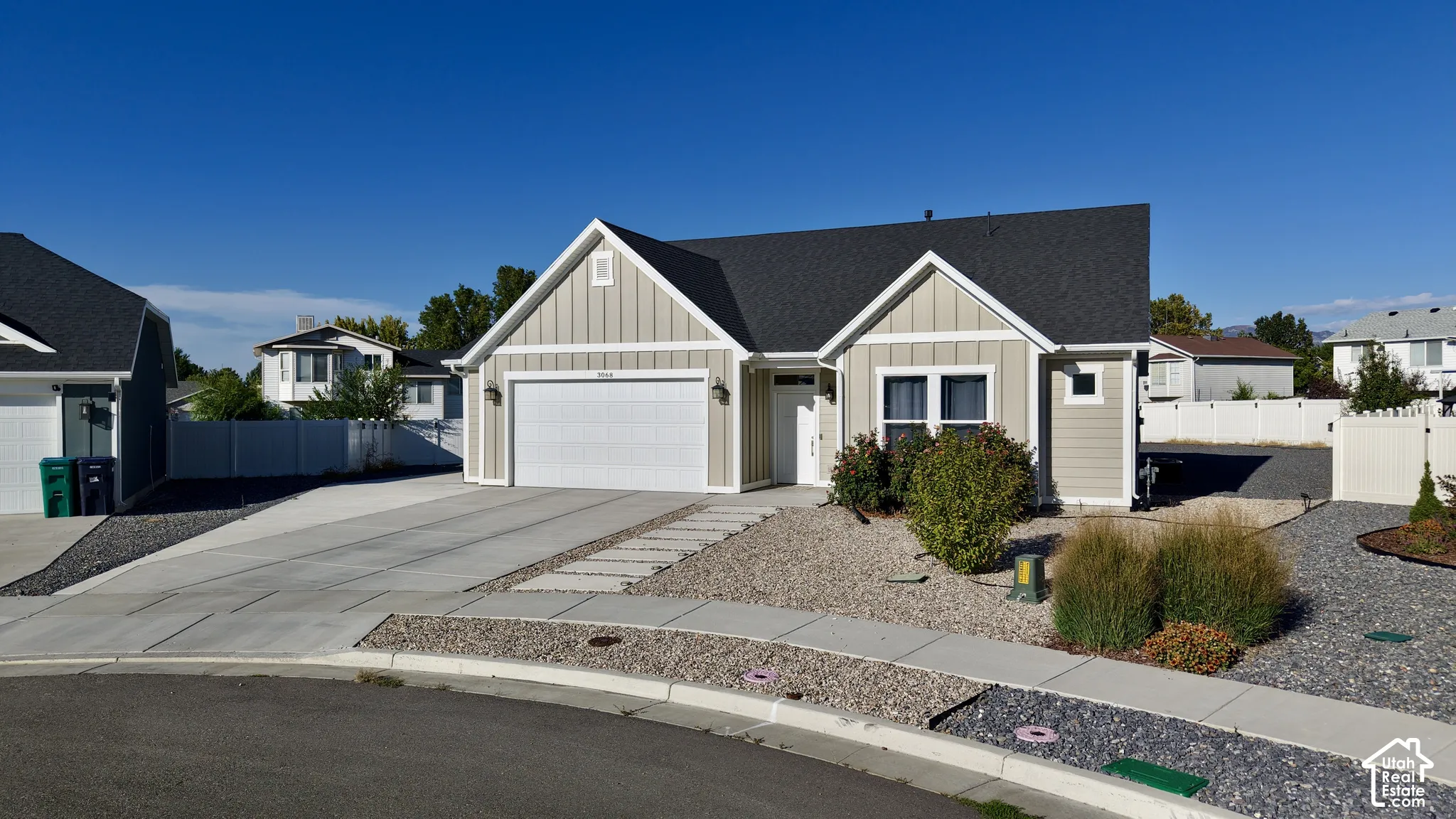 Light-toned siding exterior with a dark shingle roof, attached garage, and a concrete driveway