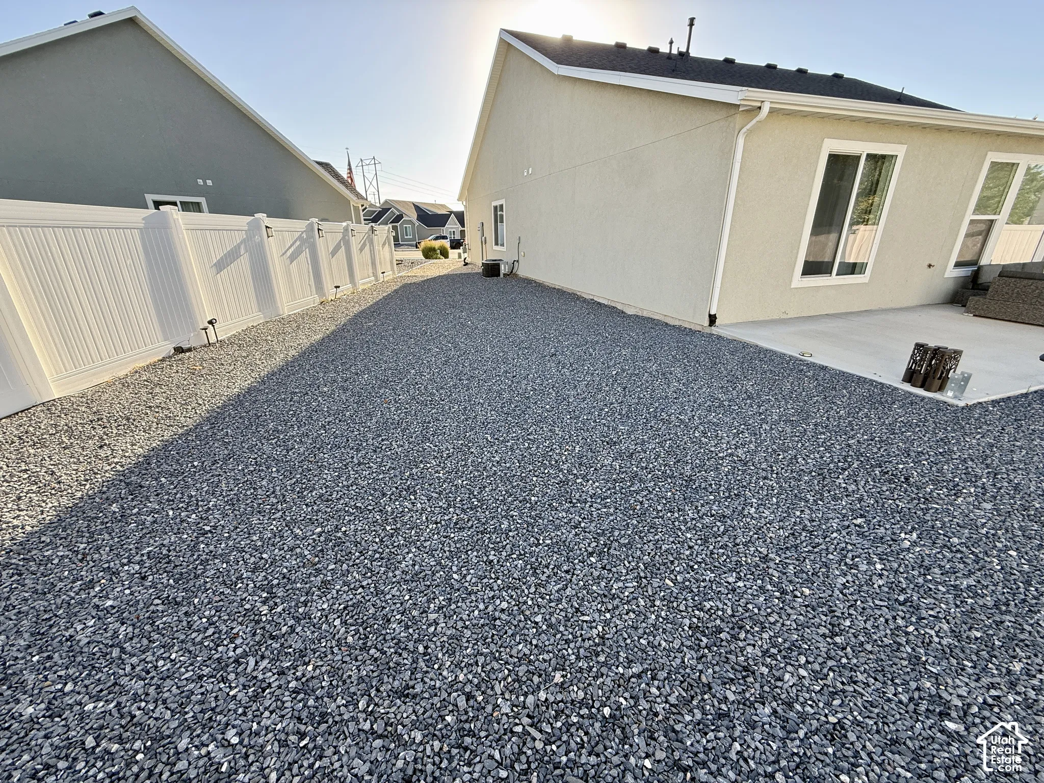 Gravel hardscaping with a white vinyl fence and a concrete patio