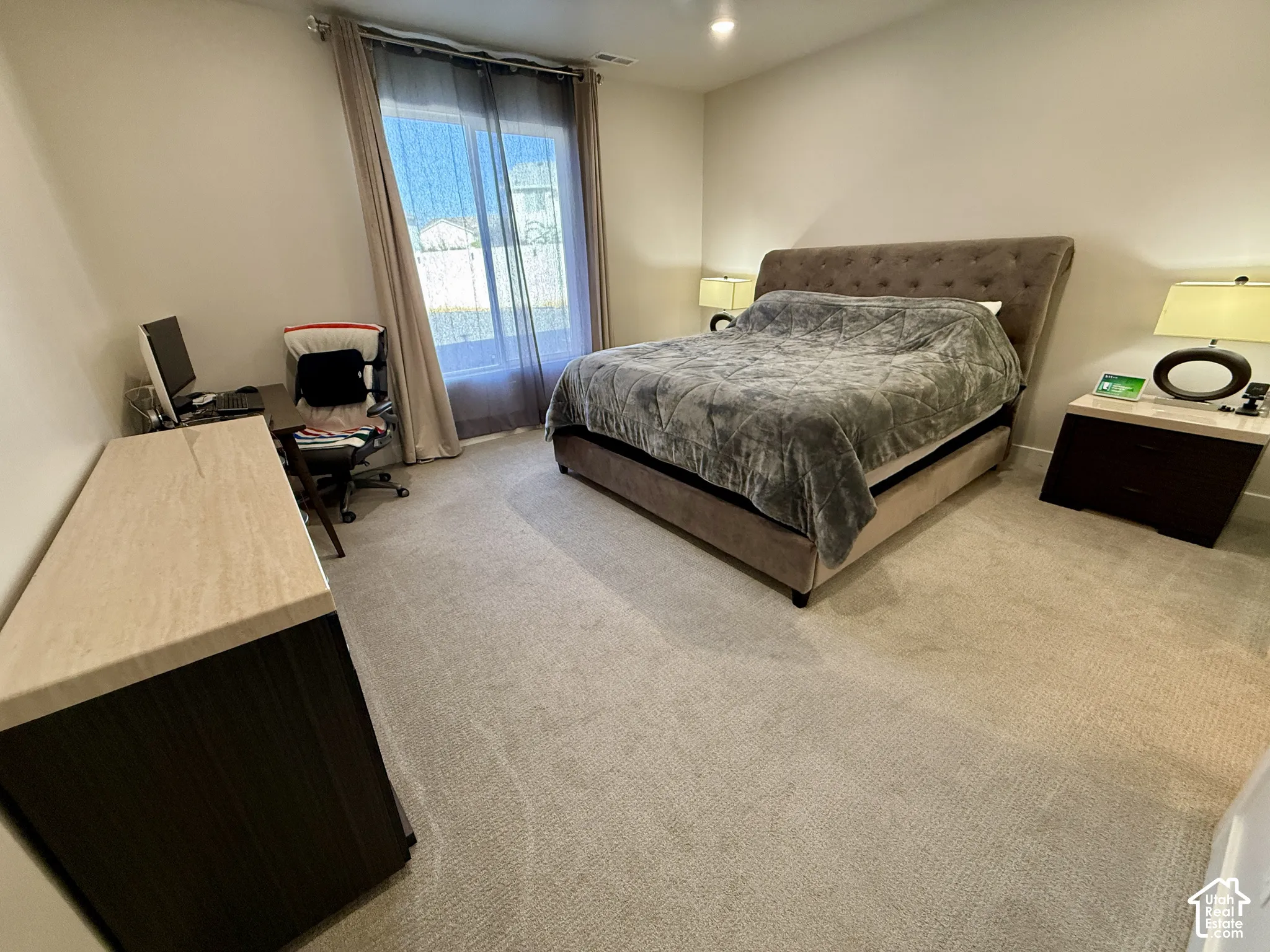 Carpeted flooring, recessed lighting, and a window with sheer and blackout curtains