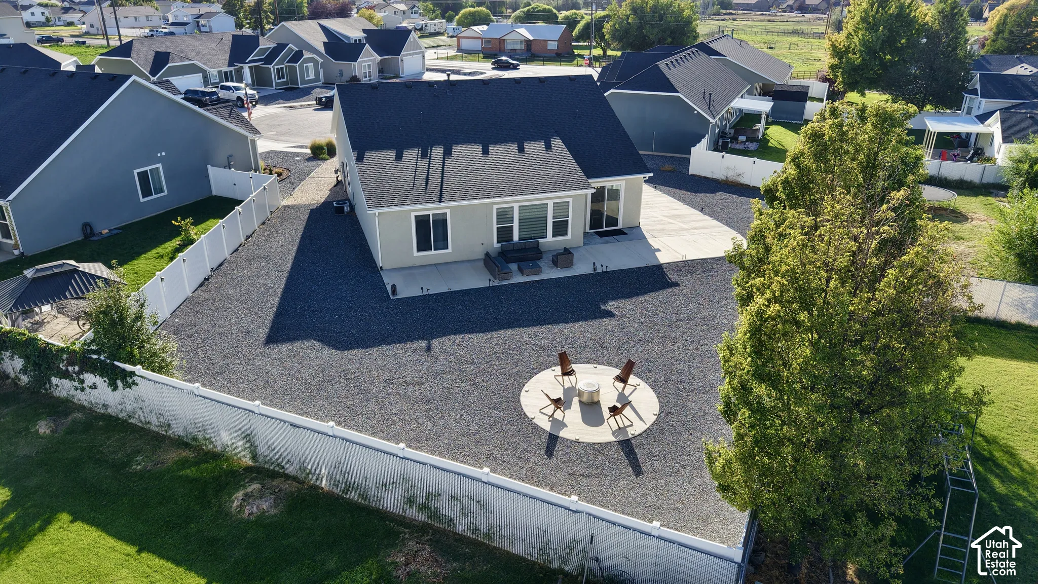 Rear exterior with a concrete patio, gravel hardscaping, and a white perimeter fence