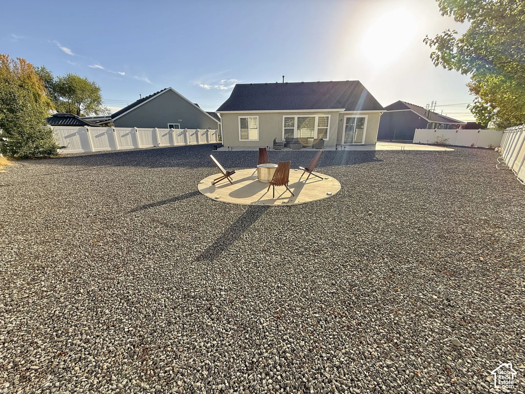 Expansive backyard featuring a gravel landscape, a circular concrete patio, and full vinyl fencing