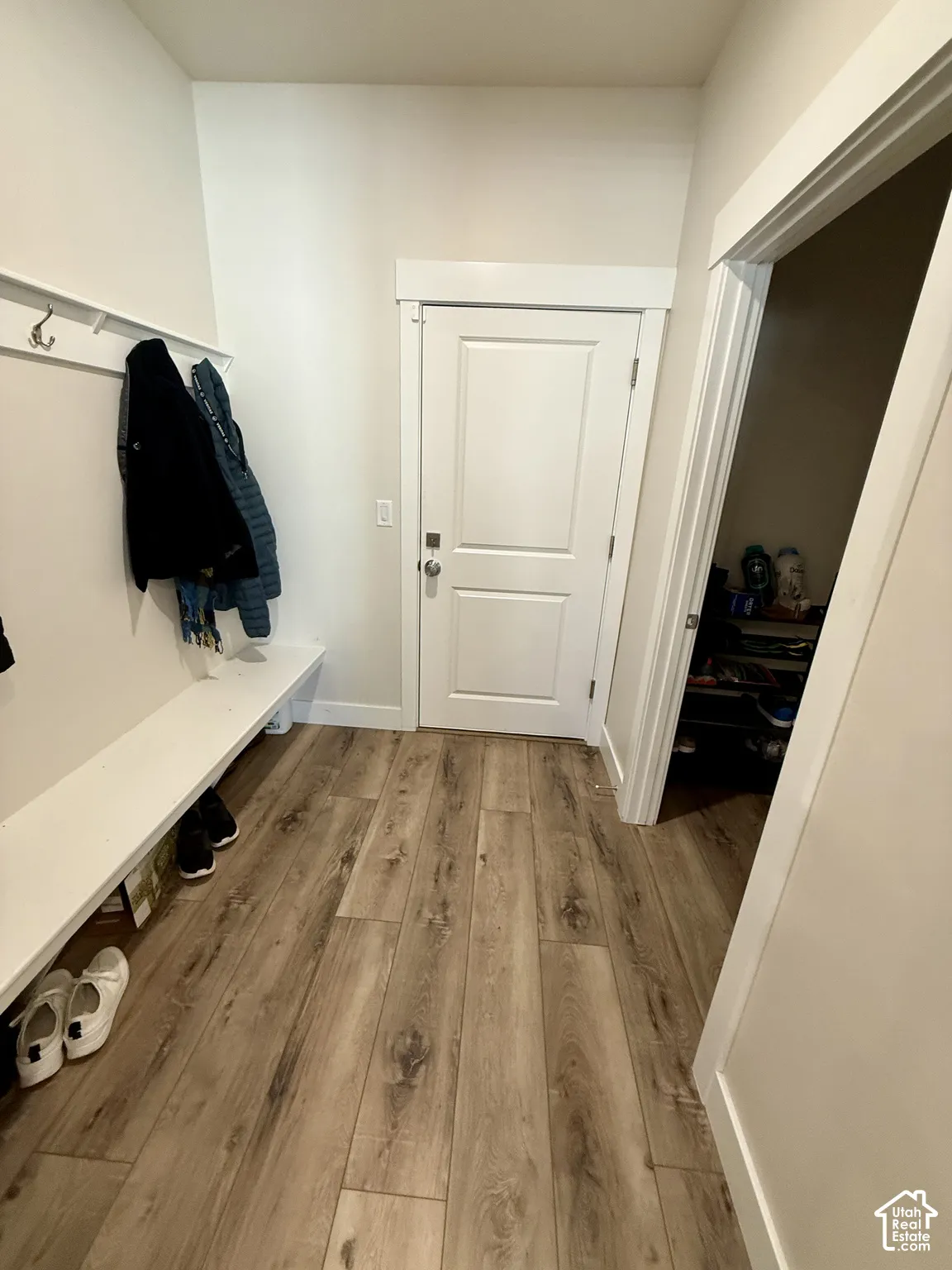 Wood-finish flooring, white built-in bench, white shaker-style door, and white trim