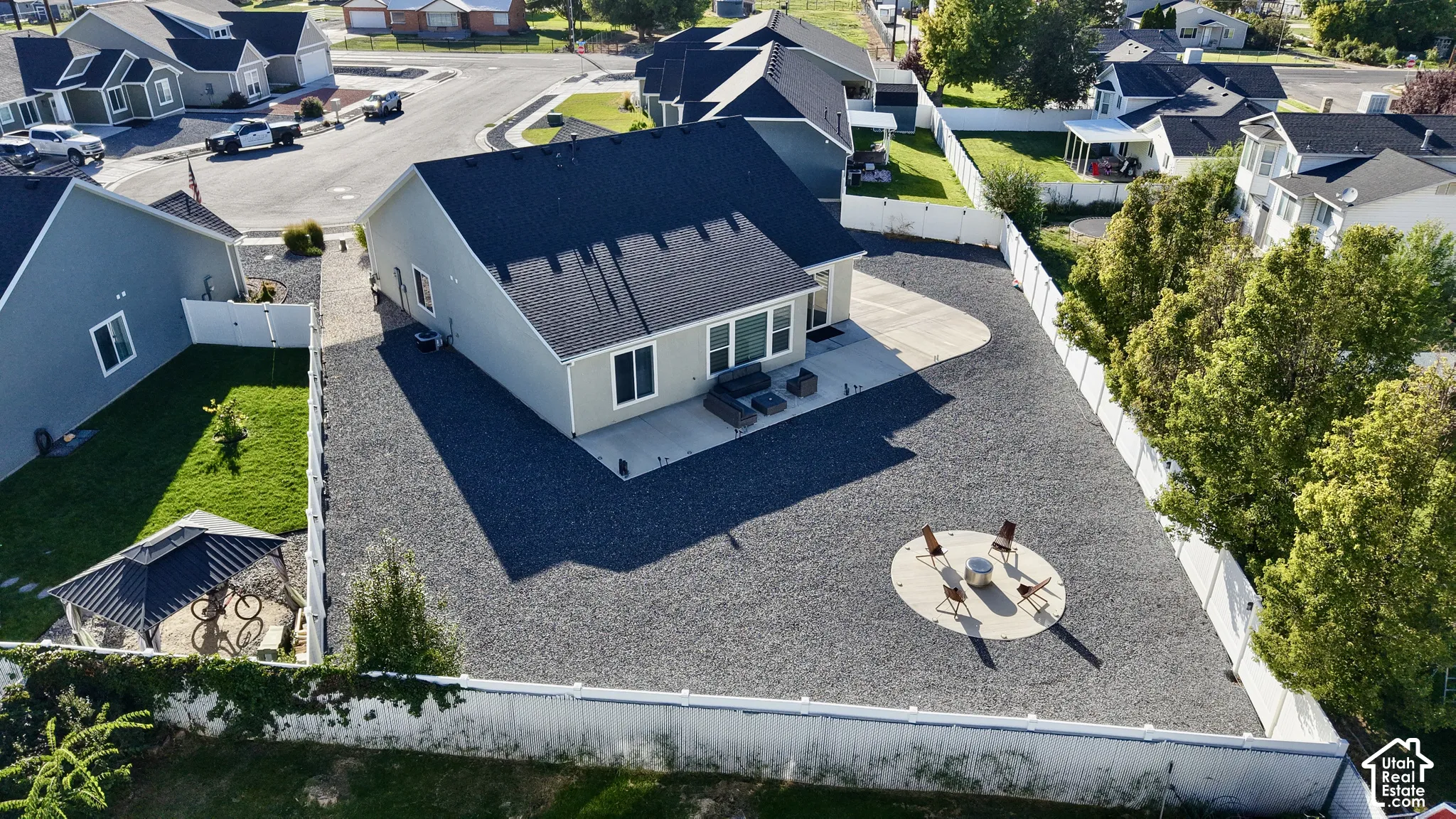 Expansive gravel yard featuring a concrete patio, privacy fencing, and a circular fire pit area