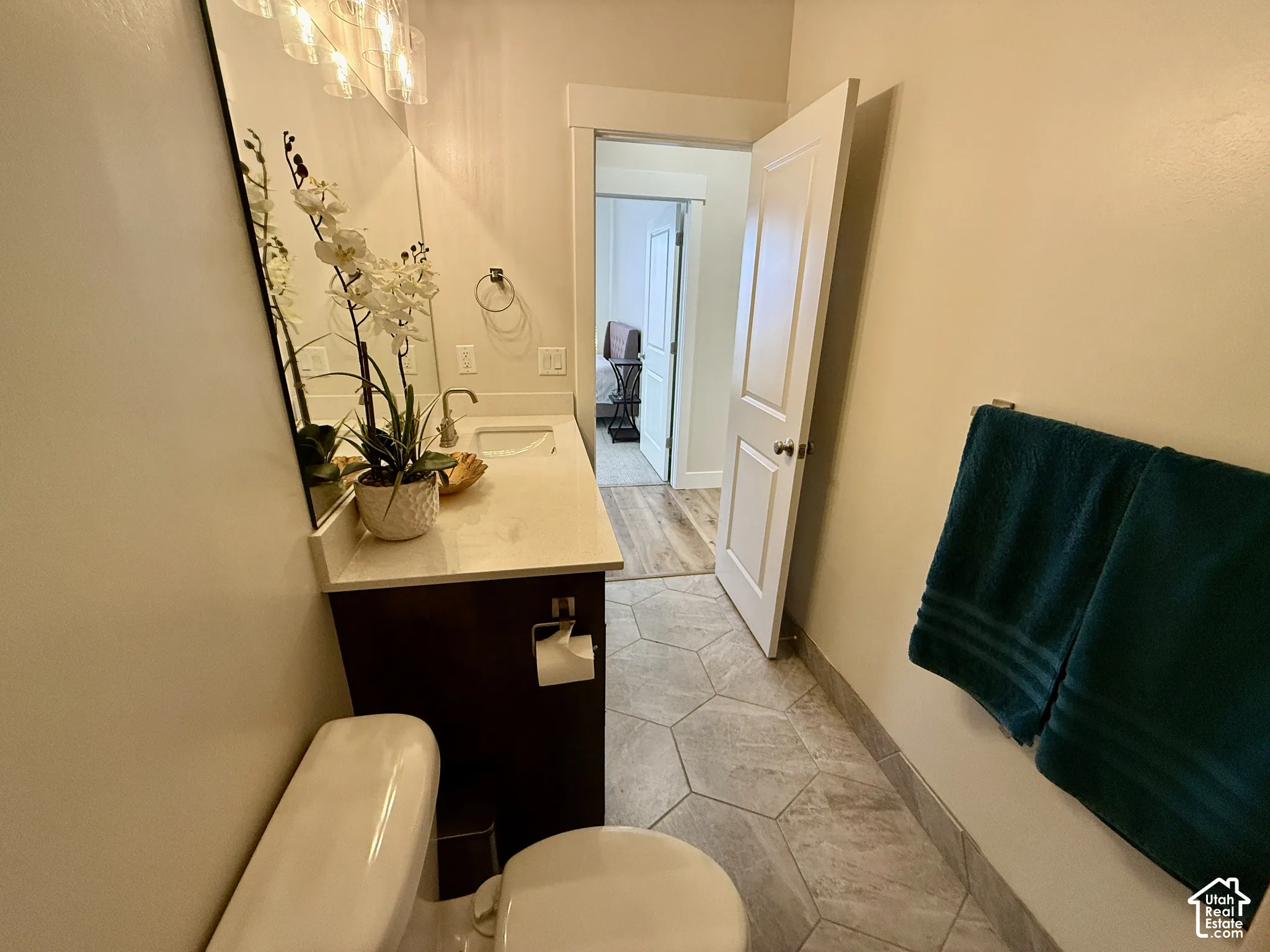 Hexagonal tile flooring, dark wood-finish vanity, light-toned countertop, integrated sink, and modern vanity lighting