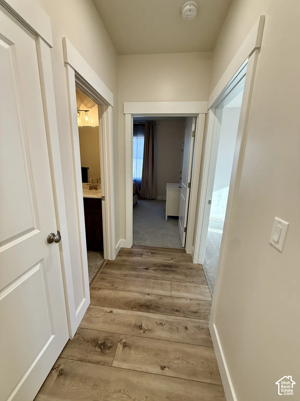 Hallway with wood-finish flooring, white trim, and light-toned walls