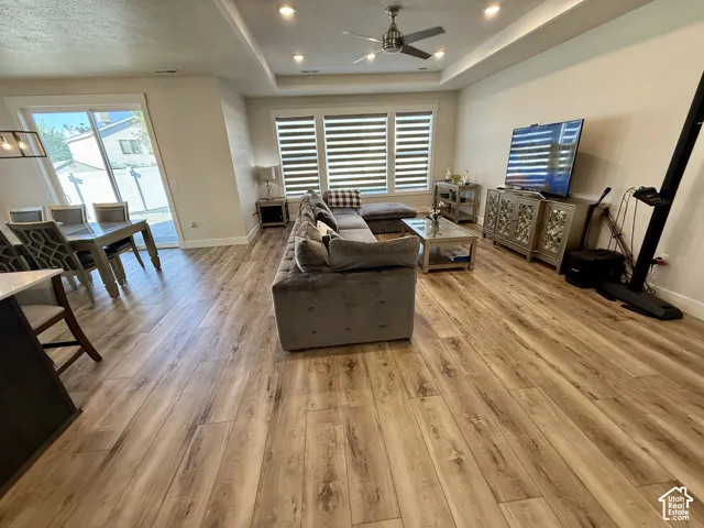 Open-concept living area featuring wood-finish flooring, recessed lighting, and a tray ceiling