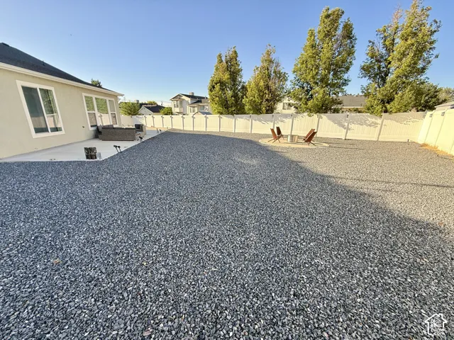 Expansive backyard featuring a gravel surface, concrete patio, and privacy fencing