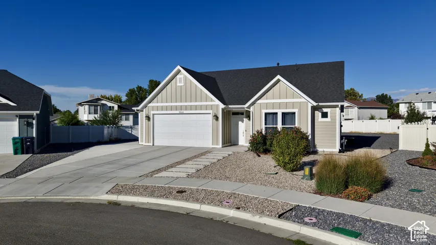 Light-toned siding exterior with a dark shingle roof, attached garage, and a concrete driveway