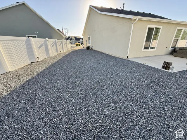 Gravel hardscaping with a white vinyl fence and a concrete patio