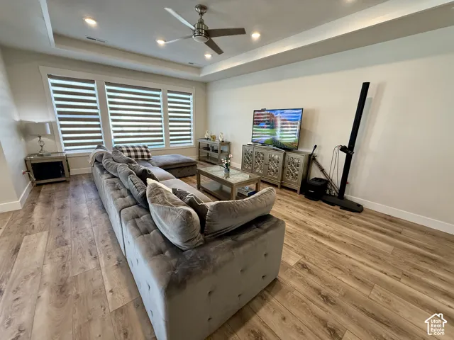 Wood-finish flooring, recessed lighting, ceiling fan, tray ceiling, and white trim