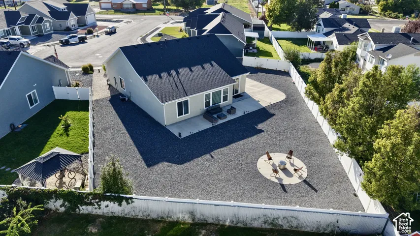 Expansive gravel yard featuring a concrete patio, privacy fencing, and a circular fire pit area