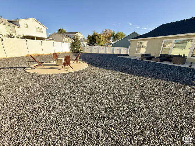 Expansive gravel landscaping featuring a concrete patio, integrated fire pit, and durable vinyl fencing