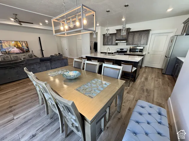 Open-concept living space with wood-finish flooring, a kitchen island with seating, dark wood cabinetry, stainless steel appliances, and recessed lighting
