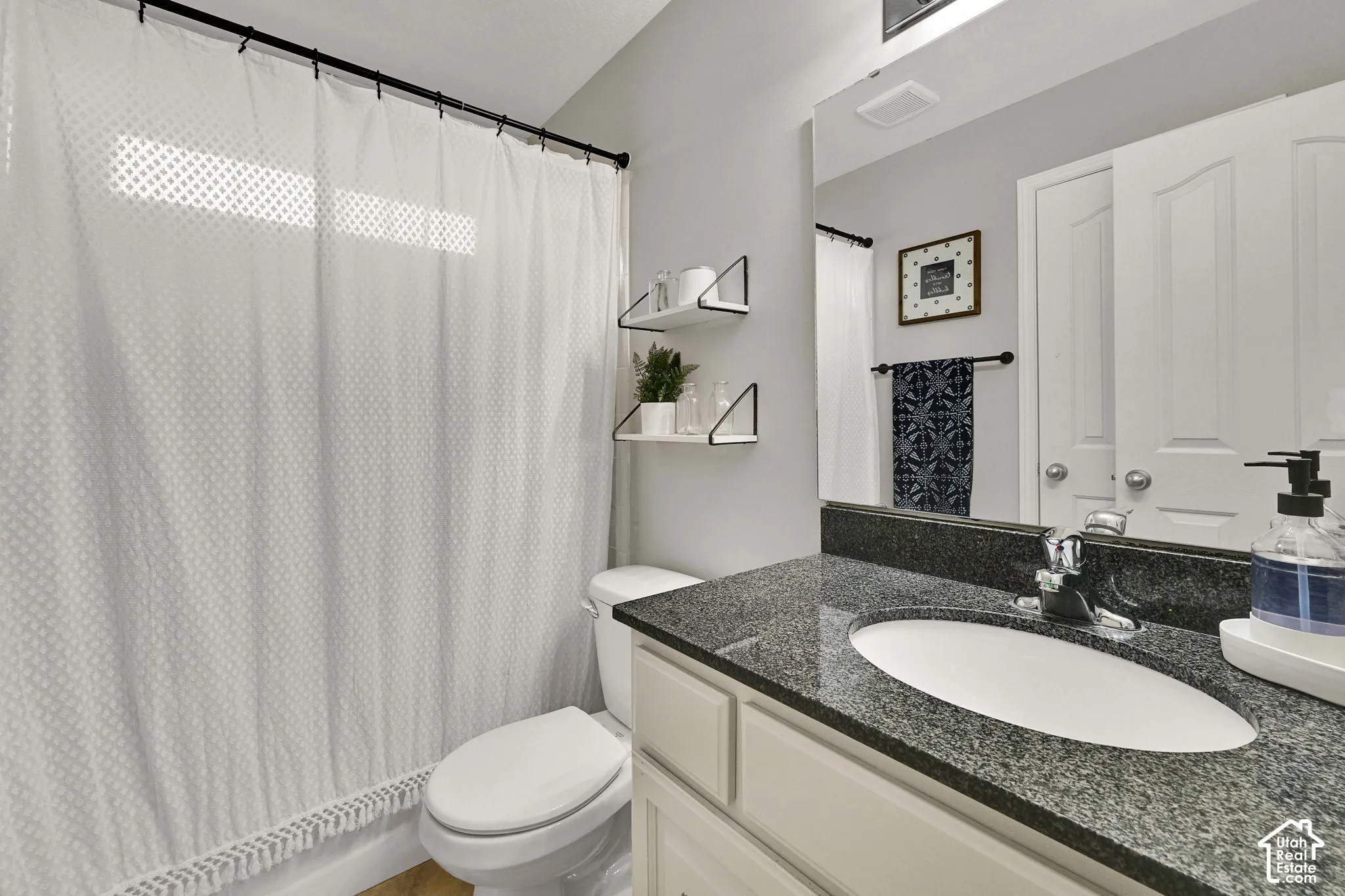 Vanity with a granite countertop, undermount sink, and chrome faucet