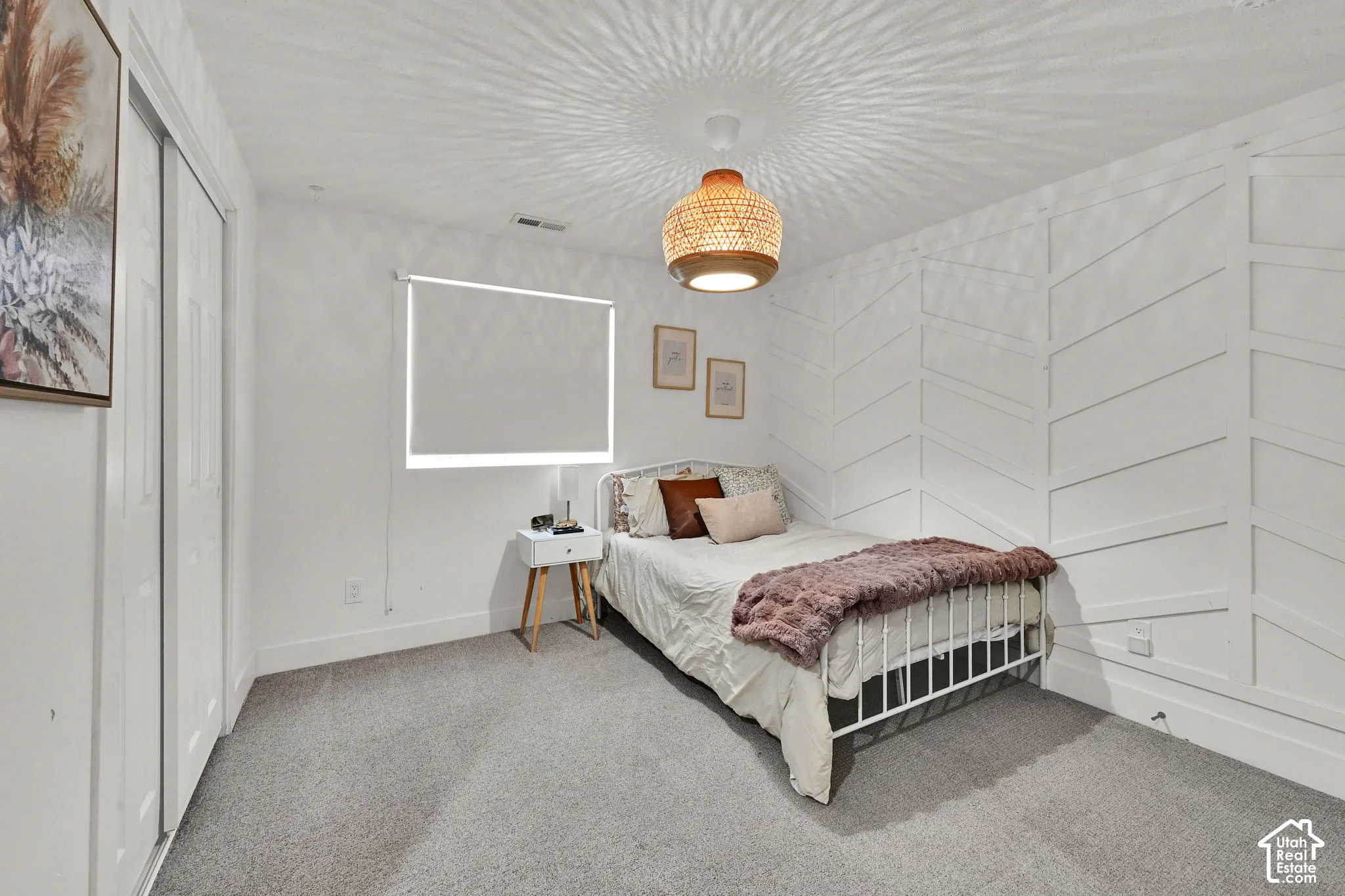 White paneled accent wall, ceiling-mounted light fixture, and roller shade window covering