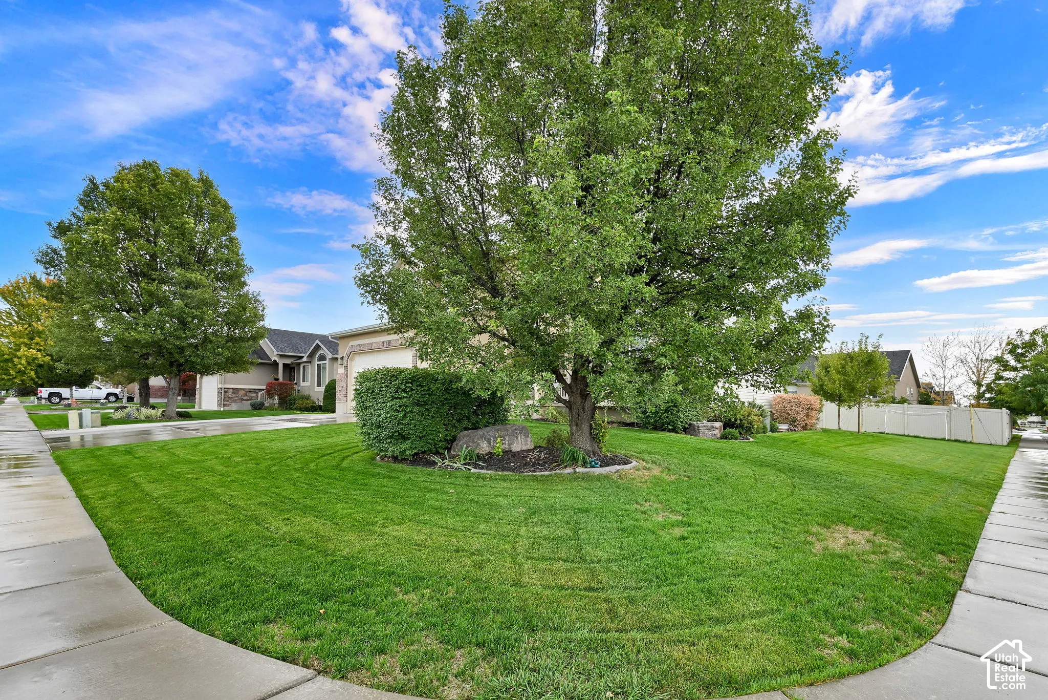 Expansive corner lot featuring a verdant lawn, mature trees, and RV pad