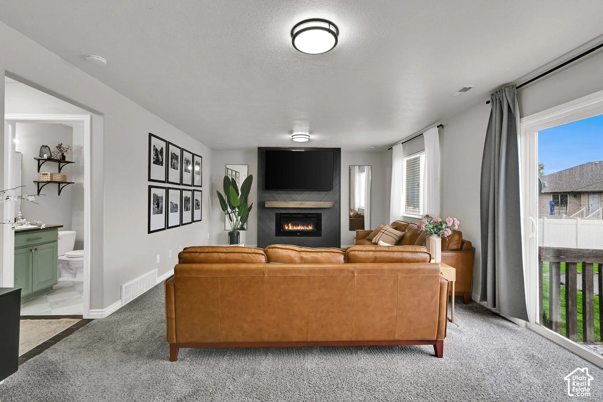 Recessed fireplace with hearth, built-in television mount, sliding glass patio door, and flush-mount ceiling lighting
