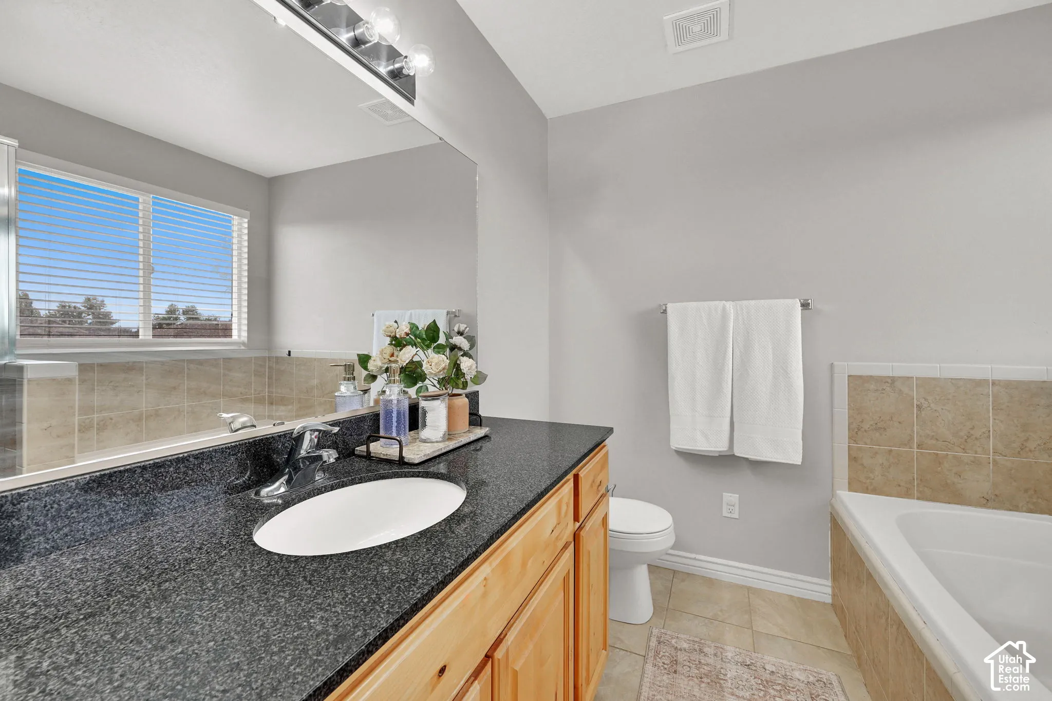 Wood-finish vanity with an undermount sink, dark speckled countertop, and chrome faucet