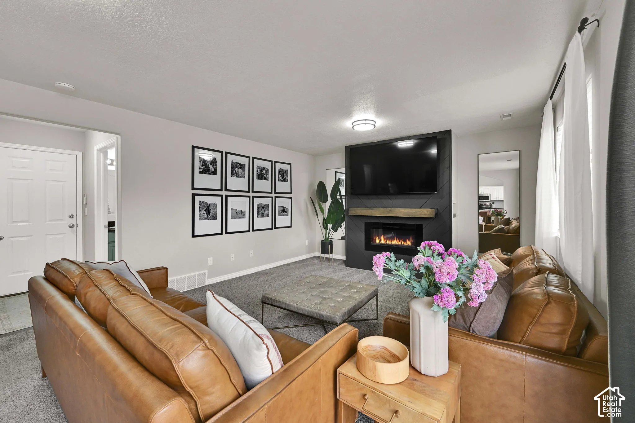 Living space featuring a built-in electric fireplace, wall-mounted television, and a wood mantel
